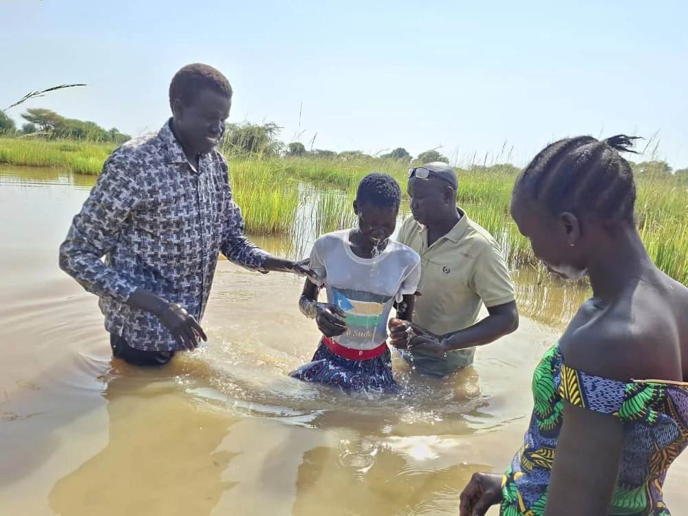 A baptism taking place with community members nearby